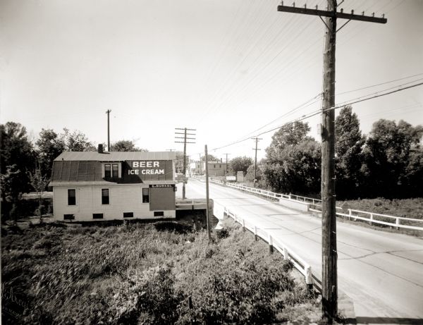 Elevated view of the outskirts of an unidentified town in the vicinity of Green Bay. The sign painted on the roof of the building on the left reads: "Beer Ice Cream".