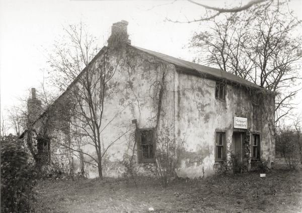 Southwest view of the Jeremiah Curtin house at 8685 West Grange Avenue. This stone and stucco residence was erected in 1835. It has been recognized as the boyhood home of linguist and mythologist Jeremiah Curtin. A sign above the doorway reads: "Birthplace of Jeremiah Curtin".