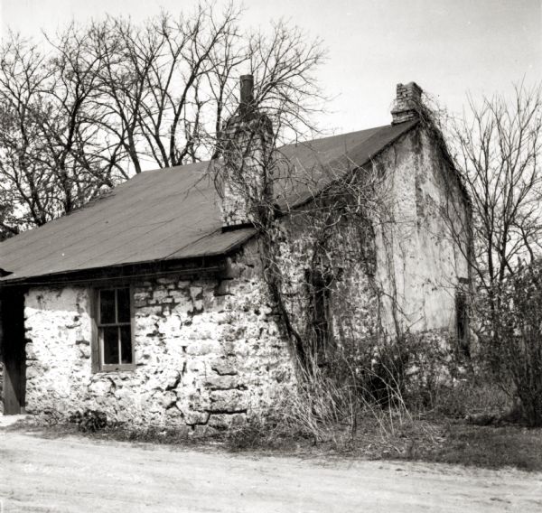 Rear view of the Jeremiah Curtin house at 8685 West Grange Avenue showing the kitchen lean-to. This stone and stucco residence was erected in 1835. It has been recognized as the boyhood home of linguist and mythologist Jeremiah Curtin.