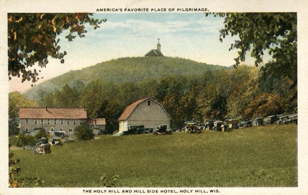 View of Holy Hill, with a field and the Hillside Hotel in the foreground. Captions read: "America's Favorite Place of Pilgrimage" and "The Holy Hill and Hill Side Motel, Holy Hill. Wis."