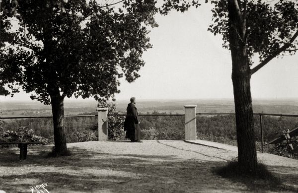 View of a man standing at a fence and looking out over the land below Holy Hill.