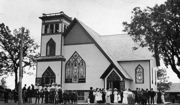 View of a Methodist church with a group of people gathered in front of it.