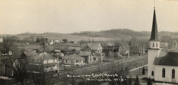 Elevated view of Whitehall from the Court House. A church is in the right foreground, and hills are in the distance. Caption at bottom reads: "Scene from Court House".