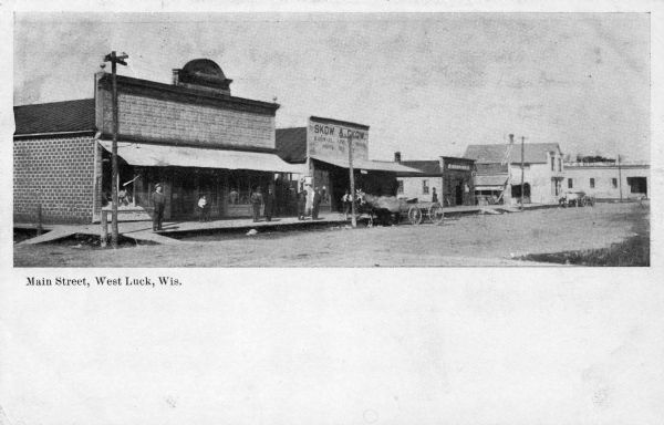 View across street towards businesses along the left. Caption reads: "Main Street, West Luck, Wis."