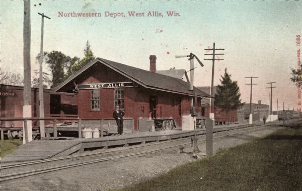 View across railroad tracks toward the buildings of the North Western railroad depot. A man is standing on the platform. Caption reads: "Northwestern Depot, West Allis, Wis."