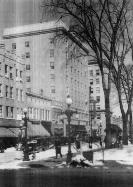 Winter view of the Wausau hotel with automobiles and people in the streets.