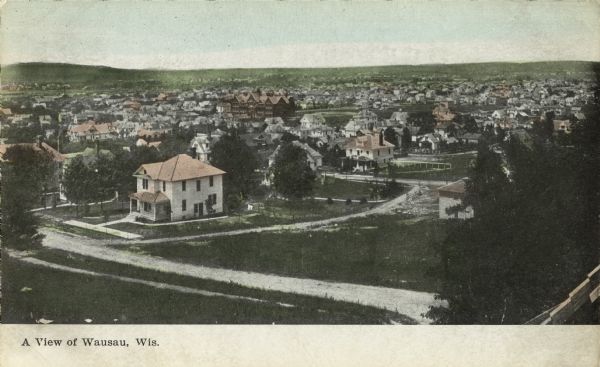 Elevated view of Wausau with the residential area in the foreground and a business district in the background. Caption reads: "A View of Wausau, Wis."