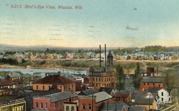 View over rooftops of town. A river is on the left, with a neighborhood on higher ground beyond. Caption reads: "Bird's-Eye View, Wausau, Wis."