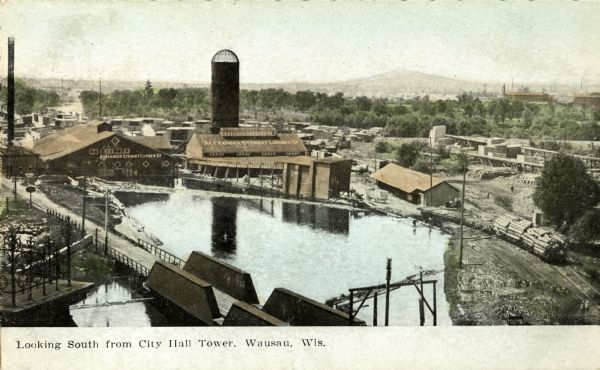 Elevated view toward the lumber company. A bridge over a river is in the foreground. Caption reads: "Looking South from City Hall Tower, Wausau, Wis."