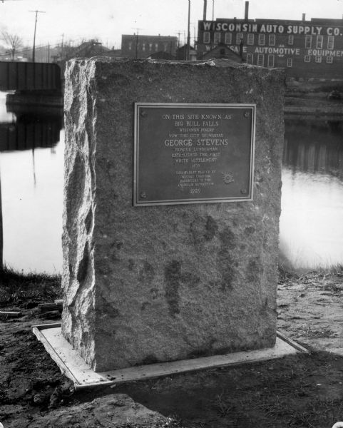 View of the George Stevens marker with the Wisconsin Auto Supply Company in the background and the Wisconsin River.