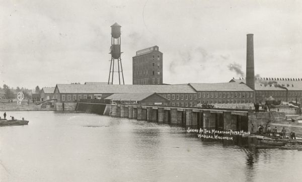 Elevated view of the Marathon Paper Mills from across the river. Caption reads: "Scene at the Marathon Paper Mills, Wausau, Wis."
