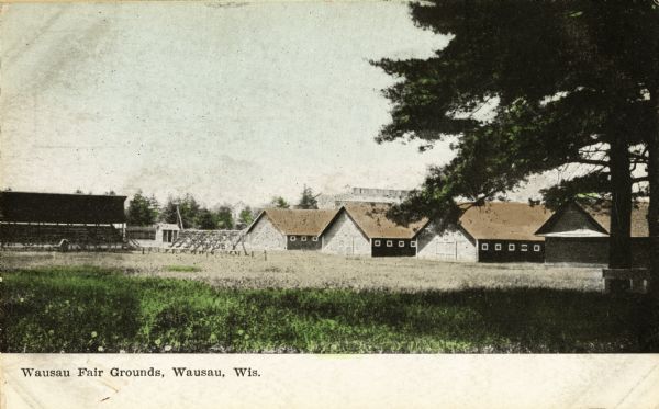 View of field area with four buildings in the background. Caption reads: "Wausau Fair Grounds, Wausau, Wis."