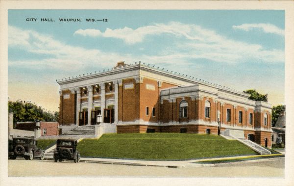 View from street towards city hall with vehicles parked in front of it. Caption reads: "City Hall, Waupun, Wis."