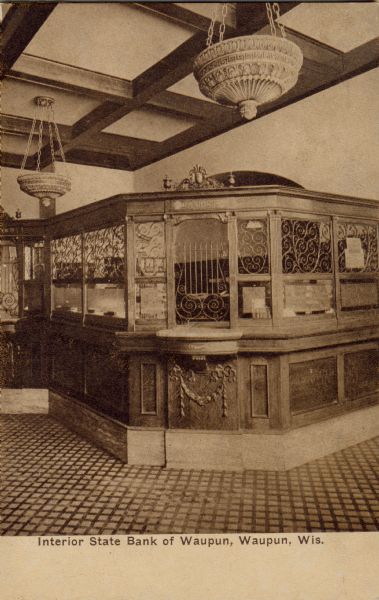Interior view of the cashier stations and light fixtures of the State Bank. Caption reads: "Interior State Bank of Waupun, Waupun, Wis."