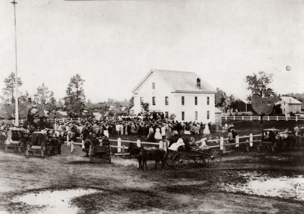 View of an unidentified ceremony taking place at the public square on the steps of the original Waupaca County Courthouse.