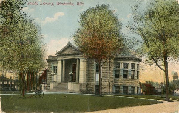 Exterior view of the Waukesha Public Library. There is a cannon on the lawn near a tree. Caption reads: "Public Library, Waukesha, Wis."