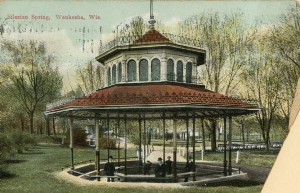 View of people at Silurian Spring, located in Waukesha Springs Park. Caption reads: "Silurian Spring, Waukesha, Wis."