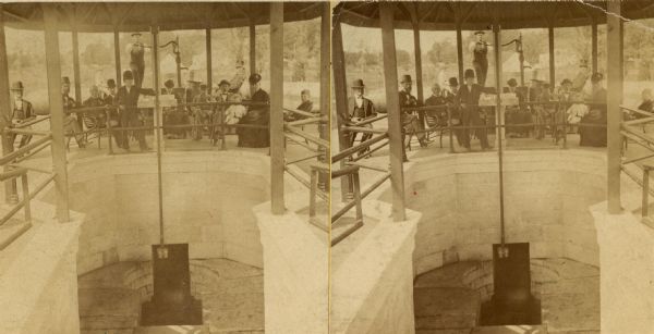 Stereograph view of Glenn's mineral spring with a group of people gathered around it.