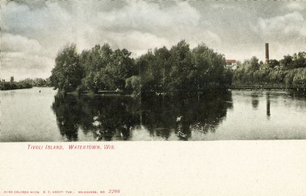 View across water towards Tivoli Island. There is a smokestack and a building among trees in the distance. Caption reads: "Tivoli Island, Watertown, Wis."