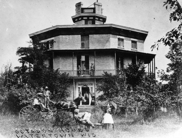 Exterior view of the Richards' Octagon House, with a horse and carriage and various people posed in front of it. Caption reads: "Octagon House Watertown Wis."