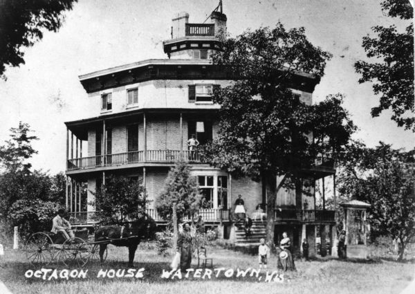 Exterior view of the Octagon House with a horse and carriage posed in the foreground and several people around it and on its porches. Caption reads: "Octagon House Watertown, Wis."