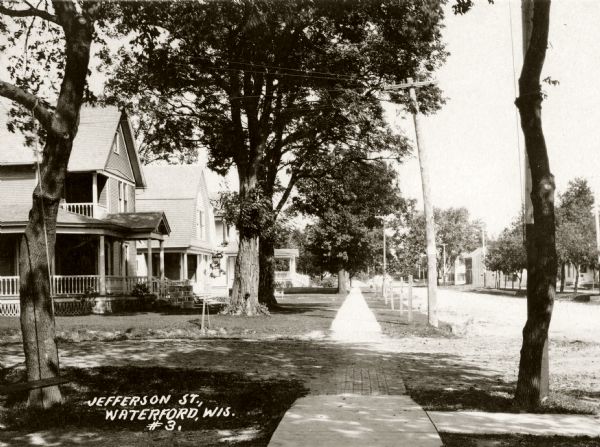 View down sidewalk along the left side of Jefferson Street. Caption reads: "Jefferson St., Waterford, Wis."
