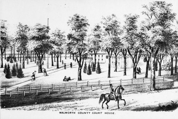 Slightly elevated engraved view of the Walworth County Courthouse. In the foreground a man is riding a horse along the street. Pedestrians are on the grounds of the courthouse, which has sidewalks, trees and bushes. Caption reads: "Walworth County Court House."