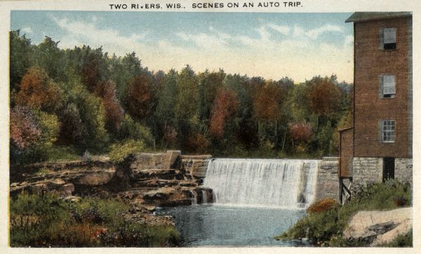 View of a dam surrounded by autumnal trees. An industrial building is on the right. The scene is Shoto Falls, in the Town of Shoto, near Two Rivers. Caption reads: "Two Rivers, Wis. Scenes on an Auto Trip."