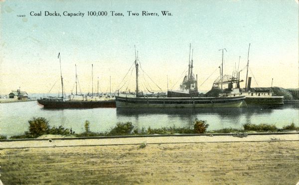 View from shoreline towards the coal docks on the right, with several ships in the harbor. Caption reads: "Coal Docks, Capacity 100,000 Tons, Two Rivers, Wis."