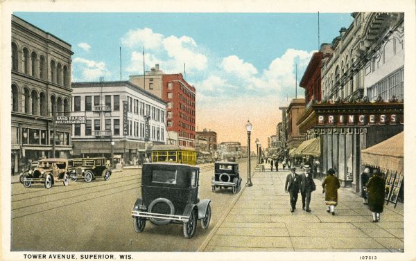 View from sidewalk looking across Tower Avenue. A theater is in the right foreground, a furniture store is located on the left side of the street and a shoe store is in the distance on the right. Caption reads: "Tower Avenue, Superior, Wis."