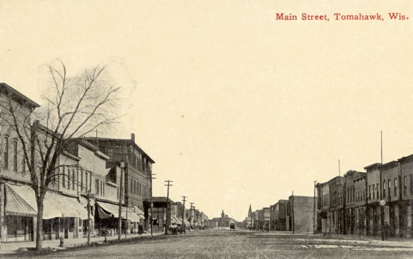View down center of unpaved street with storefronts on both sides. Caption reads: "Main Street, Tomahawk, Wis."