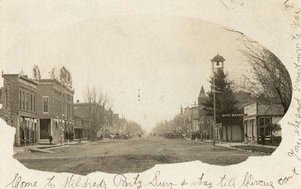 Masked view down main street, with a bakery in the right foreground.