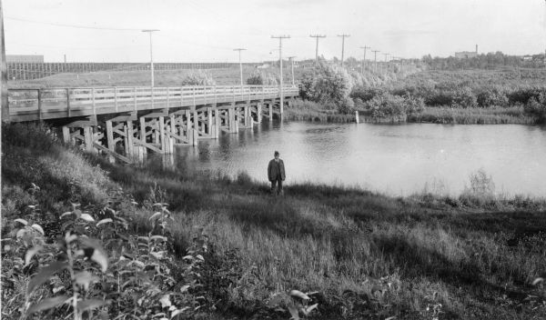Nemadji River at the foot of 2nd Avenue and Robertson Avenue. A man is standing near the grassy shoreline in the center.