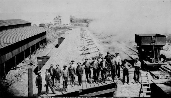 Elevated view of the coke ovens at the Lehigh Coal and Iron Company. A group of men are posing in the foreground.