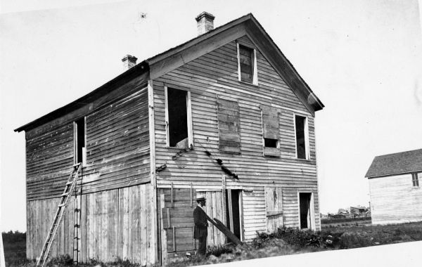 Exterior view of the Richard Bardon residence, with a man standing in front of it.