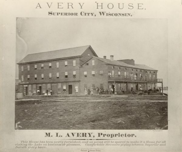 Exterior view of the Avery House, with groups of people gathered on its porches and balcony.