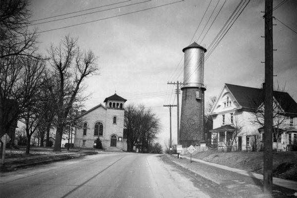 View down a street in Sun Prairie, including a home, watertower, and church.