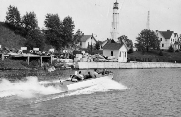 View across water towards the Sturgeon Bay Canal Lighthouse, with a group of people in a motorboat in the foreground.