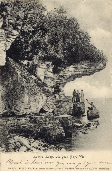 View of Lover's Leap with a group of people on the rocks near the shoreline under an overhang. Caption reads: "Lovers Leap, Sturgeon Bay, Wis."