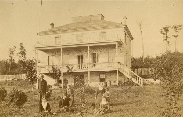 The Laurie residence, home of Mr. and Mrs. Robert Laurie, occupied by them since 1870. A group of people are posing in the grass in the foreground.