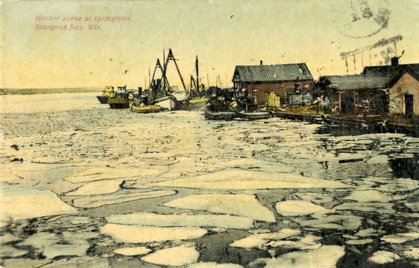 A springtime harbor scene from Sturgeon Bay. Chunks of ice are floating on the surface of the water. Caption reads: "Harbor scene at springtime. Sturgeon Bay, Wis."