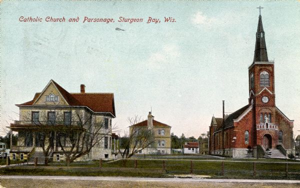 Exterior view from street towards a Catholic church and parsonage. Caption reads: "Catholic Church and Parsonage, Sturgeon Bay, Wis."