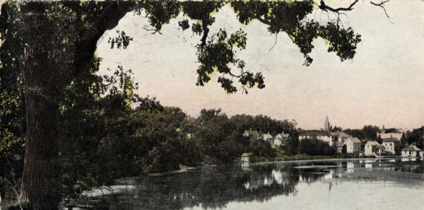 View of a mill pond with buildings in the background.