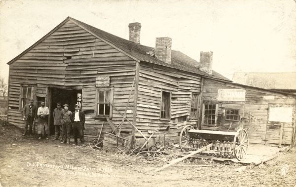 Exterior view of the Stockbridge Indian Mission with men standing near its entrance.