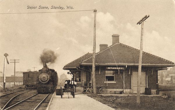 Railroad depot with train approaching the station. Caption reads: "Depot Scene, Stanley, Wis."