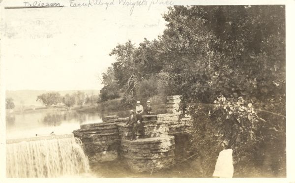 View of several people posing near the pond and spillway on the grounds of Taliesin, Frank Lloyd Wright's residence and architectural school complex. Taliesin is located in the vicinity of Spring Green, Wisconsin.