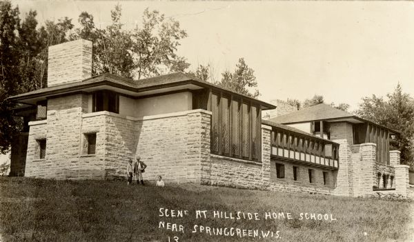 Three boys posing in front of Hillside Home School. The Hillside Home School was designed by Frank Lloyd Wright in 1901 for his aunts, Jane and Ellen Lloyd Jones. It was constructed over the next two years. Caption reads: "Scene at Hillside Home School Near Spring Green, Wis."