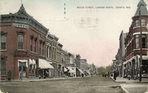 View of Water Street, featuring the Monroe County Bank on the corner on the left. Caption reads: "Water Street, Looking North, Sparta, Wis."