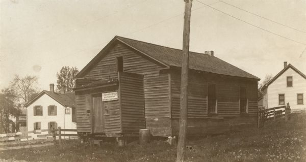 Exterior view of a school house, built in 1846. The sign on the building reads: "J. J. Koepsell Hdw. Co. House Furnishing Goods 1029 So 8 Str. Sheboygan, Wis."