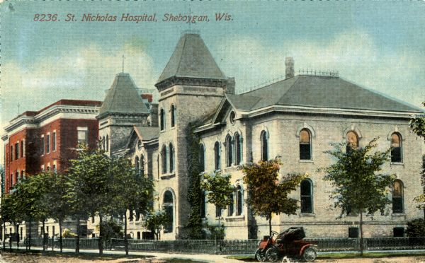Exterior view of St. Nicholas Hospital. An automobile is parked at the corner. Caption reads: "St. Nicholas Hospital, Sheboygan, Wis."